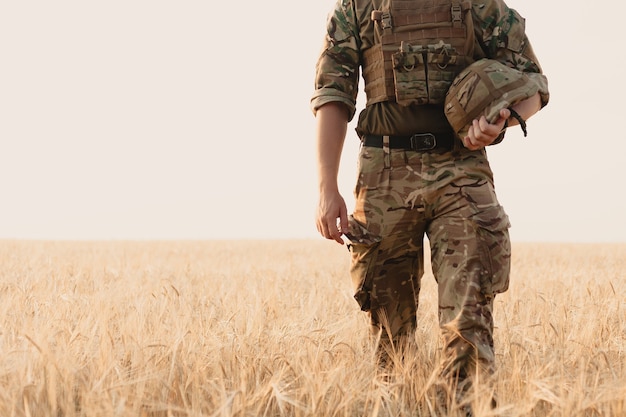 Homme soldat debout contre un champ. Portrait d'un soldat militaire heureux dans un camp d'entraînement. Soldat de l'armée américaine dans la mission. guerre et concept émotionnel.