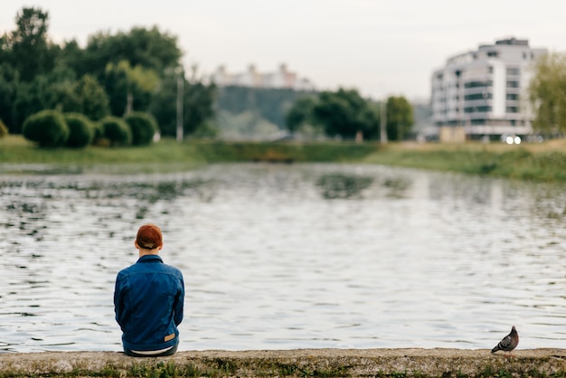 Homme solitaire assis sur le bord du remblai avec colombe