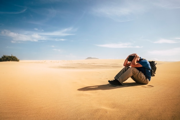 Un homme solitaire et désespéré, un routard d'aventure, s'assoit seul nulle part dans les dunes du désert - concept de changement climatique aride pour les personnes voyageant dans le beau monde - vacances de trekking extrêmes