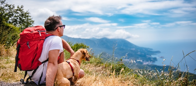 Homme et son chien assis sur la montagne et regardant la mer