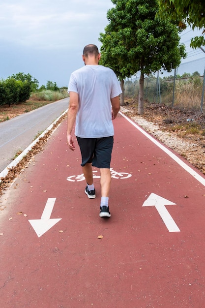 Homme sur son dos marchant sur une piste cyclable peinte avec des flèches