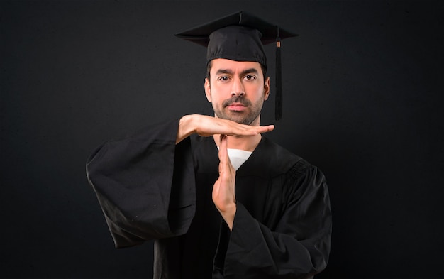 Un homme sur son jour de remise des diplômes Université fait un geste avec sa main pour arrêter un acte