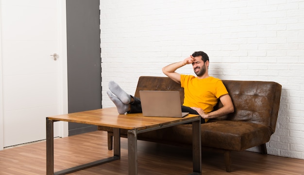 Homme avec son ordinateur portable dans une pièce avec une expression fatiguée et malade