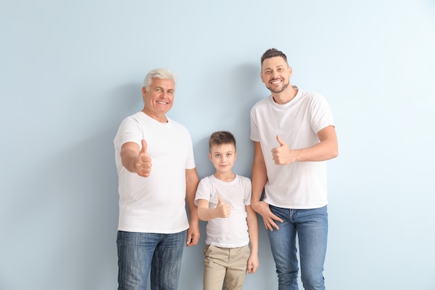 Homme avec son père et son fils montrant un geste du pouce vers le haut sur un mur de couleur