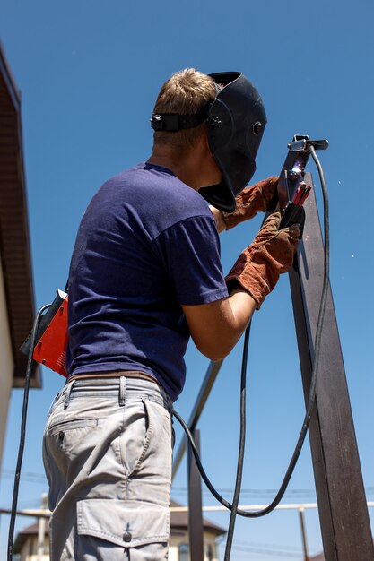 Homme soudant une construction métallique dans son jardin.