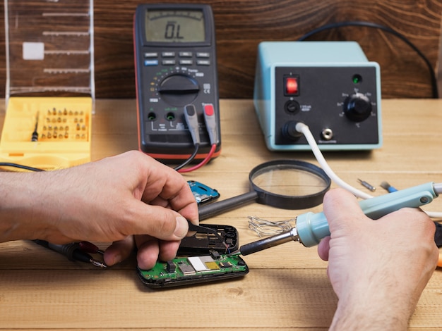 Homme souder des composants électriques dans le téléphone mobile.