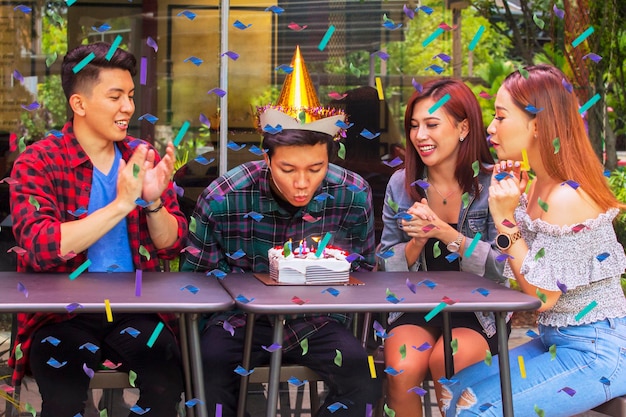 L'homme souffle des bougies avec ses amis à la fête d'anniversaire