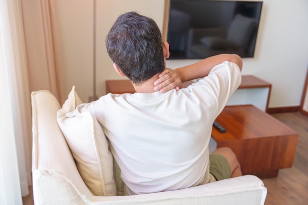 Homme souffrant de douleurs au cou et aux épaules pendant qu'il était assis sur un canapé en raison d'un rhumatisme fibromyalgique Syndrome de douleur scapulaire et concept ergonomique