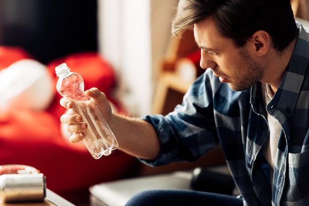 Homme souffrant de gueule de bois regardant une bouteille d'eau à la maison
