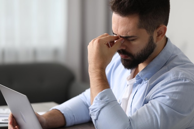 Homme souffrant de maux de tête sur le lieu de travail au bureau