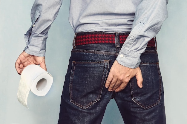 L'homme souffre de diarrhée tient un rouleau de papier toilette Le gars se tient le cul en essayant de retenir l'envie