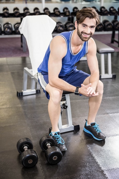 Homme souriant assis sur un banc au gymnase