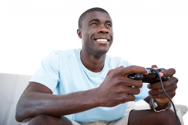 Homme souriant, assis sur un canapé à jouer à des jeux vidéo