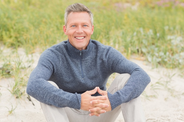 Homme souriant, assis sur le sable