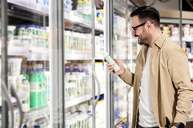 Un homme souriant choisissant des yaourts au supermarché