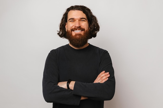 Un homme souriant et confiant aux cheveux longs est debout, les bras croisés