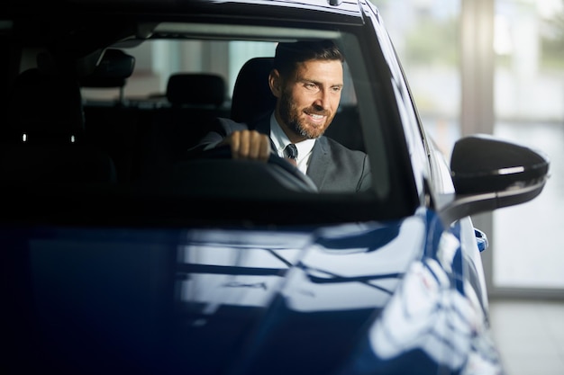 Homme souriant en costume testant une nouvelle voiture avant l'achat