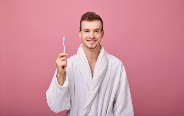 Homme souriant dans une robe blanche comme neige avec la brosse à dents