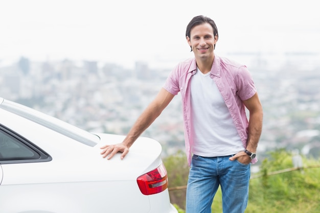 Homme souriant, debout à côté de sa voiture