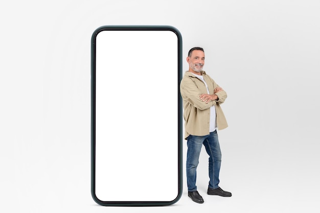 Un homme souriant debout avec une maquette de smartphone géant