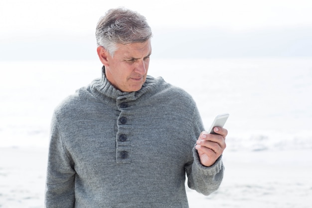 Homme souriant debout et sur son téléphone