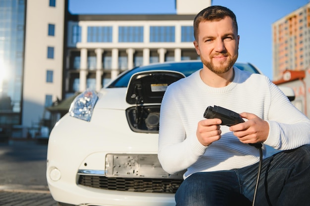 Homme souriant débranchant le chargeur de la voiture