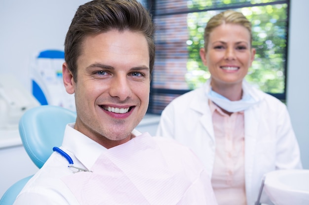 Homme souriant et dentiste assis à la clinique dentaire