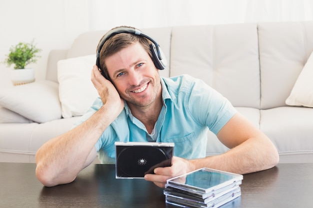 Homme souriant en écoutant des CD