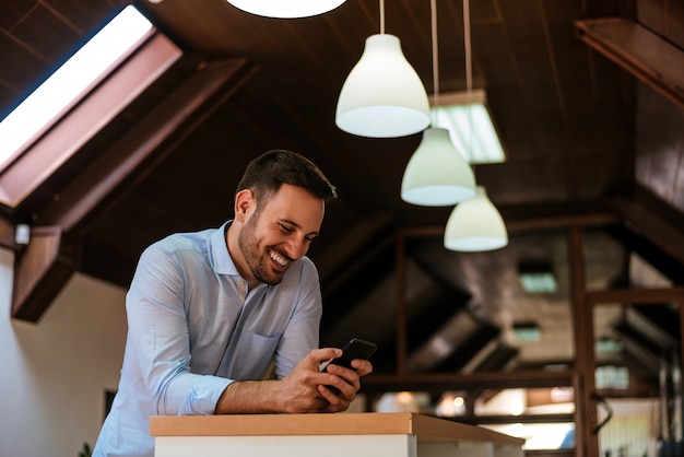 Homme souriant, envoyant un message texte à la maison