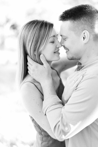 Photo un homme souriant étreint le visage d'une femme et embrasse presque son portrait en noir et blanc