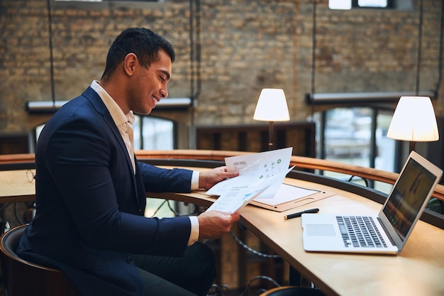 Homme souriant étudiant des documents au bureau