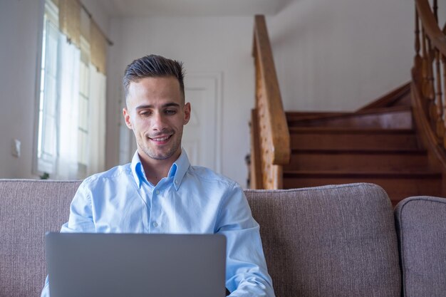 Photo homme souriant excité regardant la caméra en utilisant l'application de l'ordinateur portable en tapant un message sur le réseau social en lisant les nouvelles, en envoyant des e-mails, en discutant, en travaillant, en jouant à un jeu, en regardant des vidéos drôles.