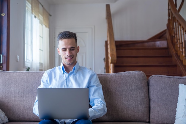 Photo homme souriant excité regardant la caméra en utilisant l'application de l'ordinateur portable en tapant un message sur le réseau social en lisant les nouvelles, en envoyant des e-mails, en discutant, en travaillant, en jouant à un jeu, en regardant des vidéos drôles.