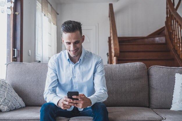 Photo homme souriant excité regardant l'écran du téléphone en utilisant une application mobile en tapant un message sur un réseau social en lisant des nouvelles, en envoyant un e-mail, en discutant avec des amis, en jouant à un jeu, en regardant des vidéos drôles.