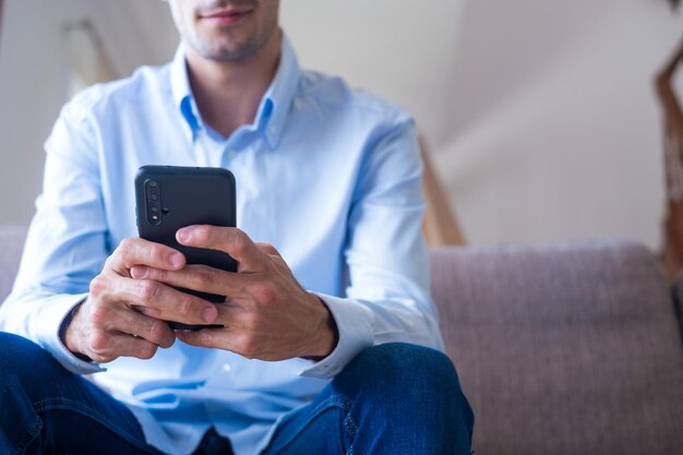 Photo homme souriant excité regardant l'écran du téléphone en utilisant une application mobile en tapant un message sur un réseau social en lisant des nouvelles, en envoyant un e-mail, en discutant avec des amis, en jouant à un jeu, en regardant des vidéos drôles.