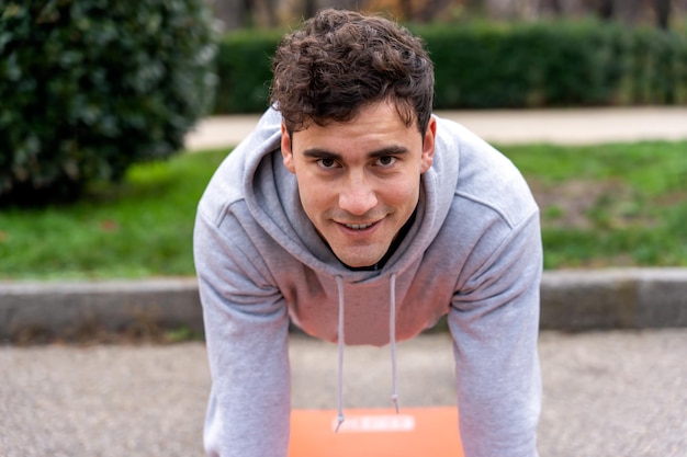 Homme souriant faisant une planche dans le parc