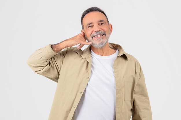 Un homme souriant fait un geste téléphonique avec sa main.