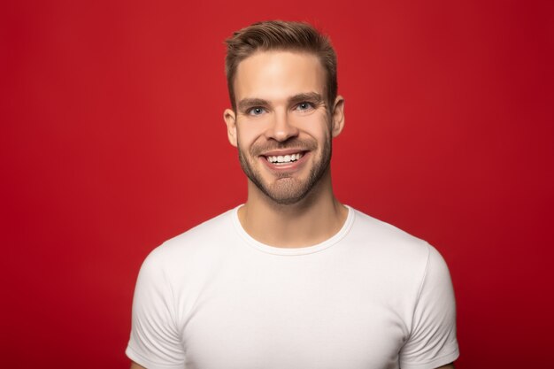 homme souriant heureux regardant la caméra isolé sur rouge