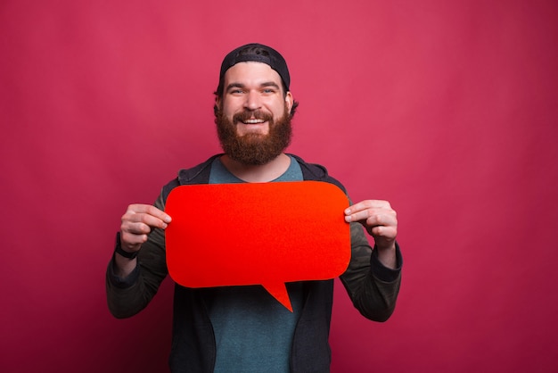 Homme souriant hipster tient un discours de bulle rouge