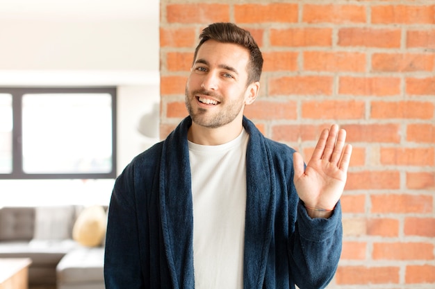 Photo homme souriant joyeusement et joyeusement, agitant la main, vous accueillant et vous saluant, ou vous disant au revoir