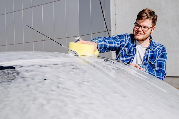 Homme souriant lavant sa voiture concept de lavage de voiture en libre-service