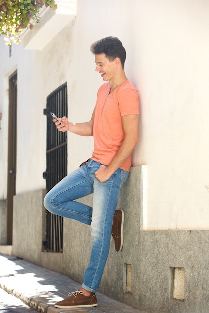 Homme souriant, lecture de SMS sur téléphone mobile