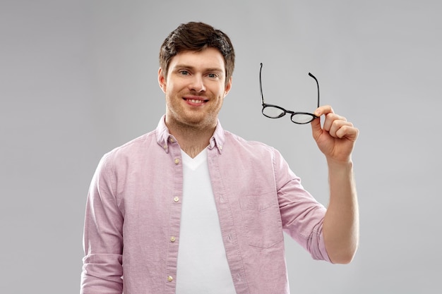 un homme souriant avec des lunettes sur un fond gris