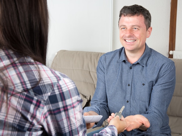 Homme souriant, obtenant les clés d'un nouvel appartement après avoir signé des documents