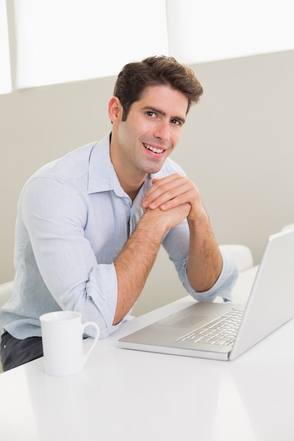 Homme souriant occasionnel à l&#39;aide d&#39;ordinateur portable à la maison