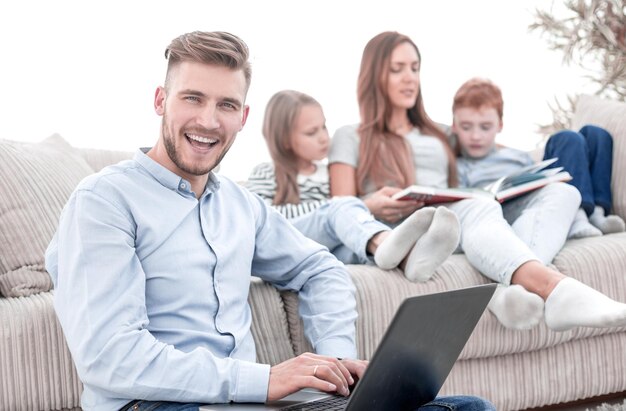 Homme souriant avec ordinateur portable assis dans son salon