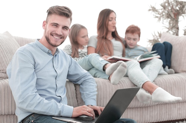 Homme souriant avec ordinateur portable assis dans son salon