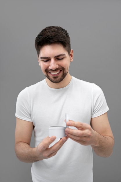 Homme souriant ouvrant un pot blanc