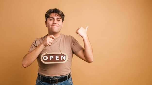 Un homme souriant avec un panneau d'invitation ouvert dans un studio beige