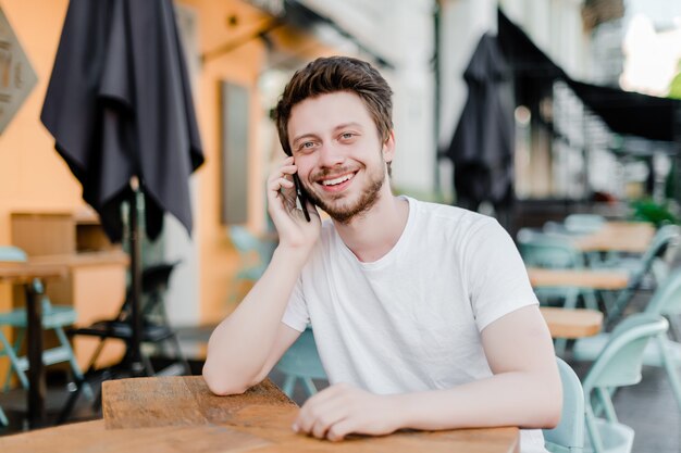 Homme souriant parle au téléphone au café